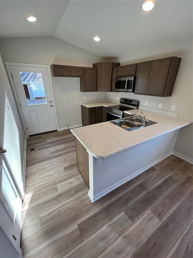 1533 Walker St, Des Moines, IA 50316 - kitchen featuring stainless steel appliances, a peninsula, light countertops, vaulted ceiling, and a sink