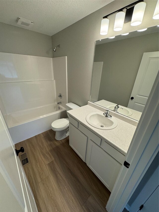 1533 Walker St, Des Moines, IA 50316 - bathroom with vanity, a textured ceiling, washtub / shower combination, and wood finished floors