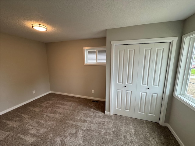 1533 Walker St, Des Moines, IA 50316 - unfurnished bedroom featuring dark carpet, multiple windows, a textured ceiling, and a closet