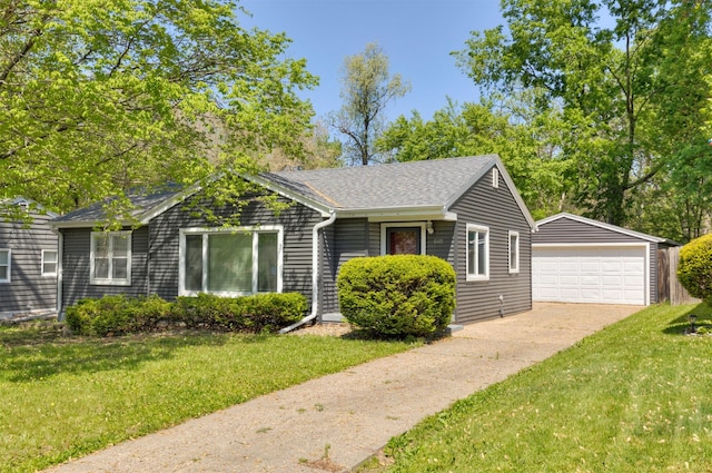 ranch-style house featuring an outbuilding, a detached garage, a front yard, and a shingled roof