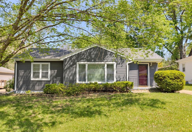 back of property featuring a lawn and roof with shingles