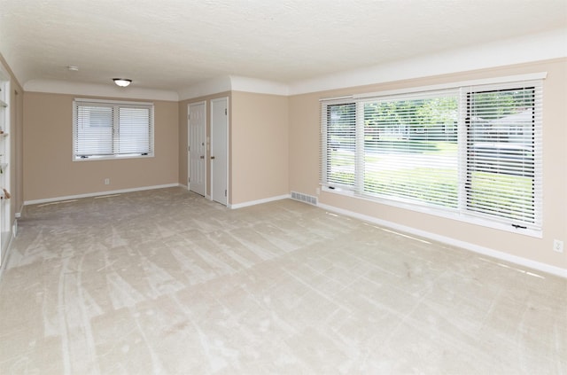 empty room with light carpet, baseboards, and a textured ceiling