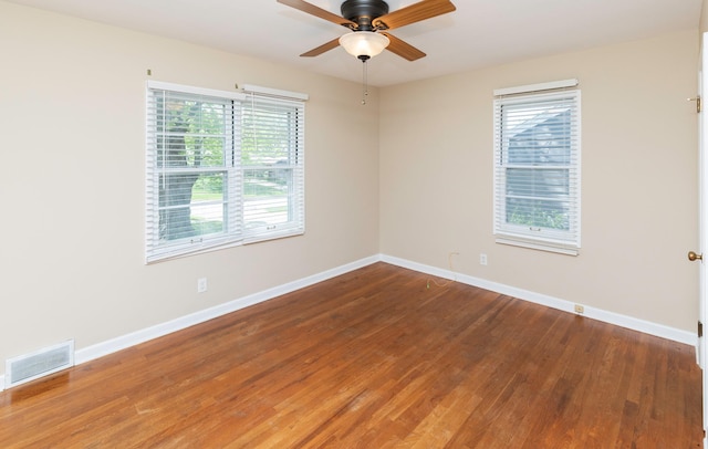 empty room featuring plenty of natural light, ceiling fan, wood finished floors, and baseboards