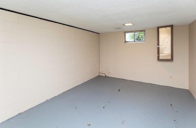 basement with a textured ceiling and concrete block wall