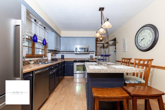 6404 Meredith Dr, Urbandale, IA 50322 - kitchen with appliances with stainless steel finishes, a sink, tasteful backsplash, light wood-type flooring, and light countertops