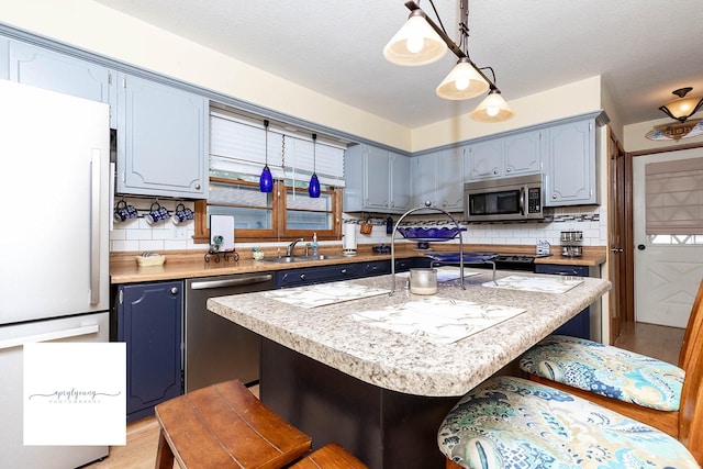 6404 Meredith Dr, Urbandale, IA 50322 - kitchen with appliances with stainless steel finishes, blue cabinets, decorative backsplash, light countertops, and a kitchen breakfast bar