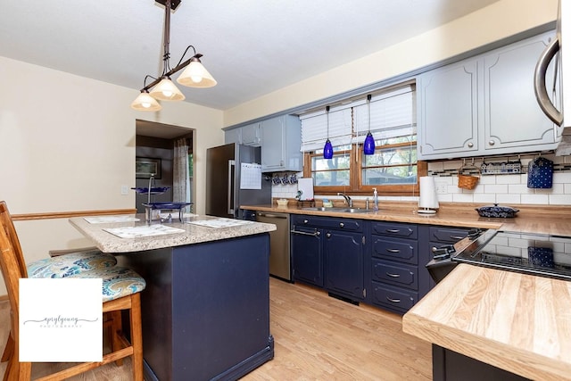 6404 Meredith Dr, Urbandale, IA 50322 - kitchen with stainless steel appliances, a sink, blue cabinets, decorative backsplash, and light wood finished floors