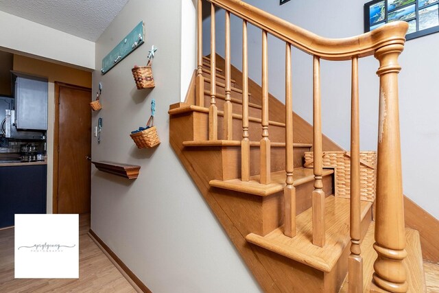 6404 Meredith Dr, Urbandale, IA 50322 - staircase featuring wood finished floors, a textured ceiling, and baseboards
