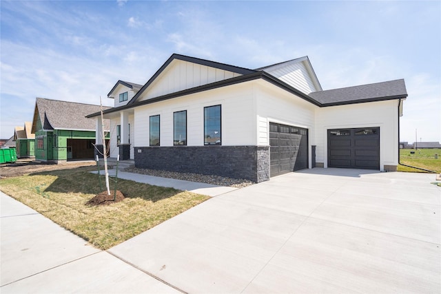 312 SW 17th St, Ankeny, IA 50023 - view of front of home with an attached garage, concrete driveway, a front lawn, board and batten siding, and stone siding