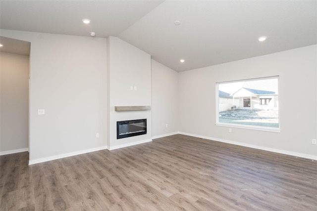 312 SW 17th St, Ankeny, IA 50023 - unfurnished living room featuring wood finished floors, a glass covered fireplace, vaulted ceiling, recessed lighting, and baseboards