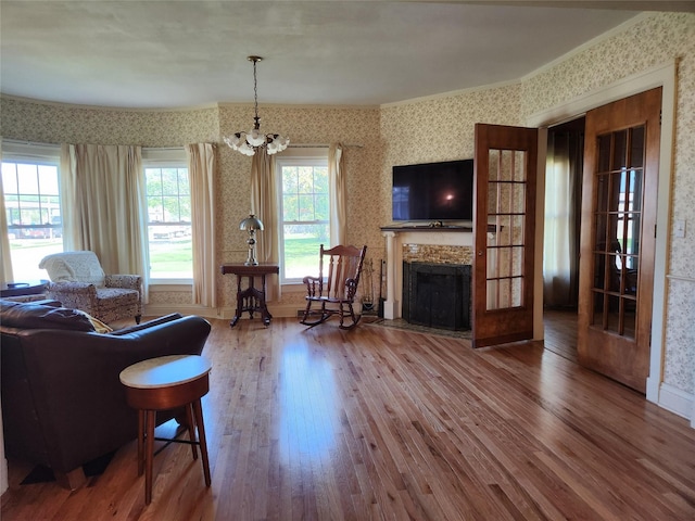 903 Greene St, Adel, IA 50003 - living area with wallpapered walls, wood finished floors, a chandelier, baseboards, and a fireplace with flush hearth