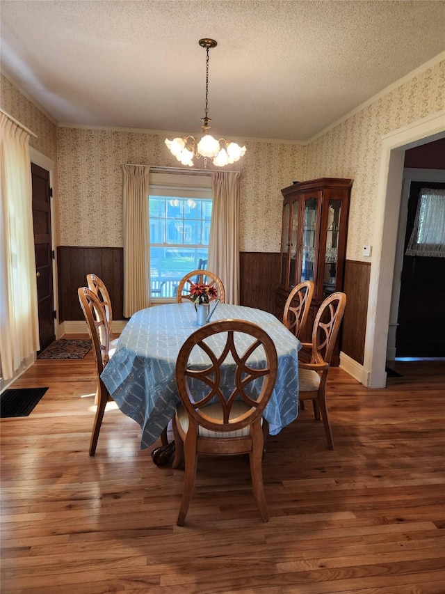 903 Greene St, Adel, IA 50003 - dining area featuring a wainscoted wall, a chandelier, a textured ceiling, wood finished floors, and wooden walls