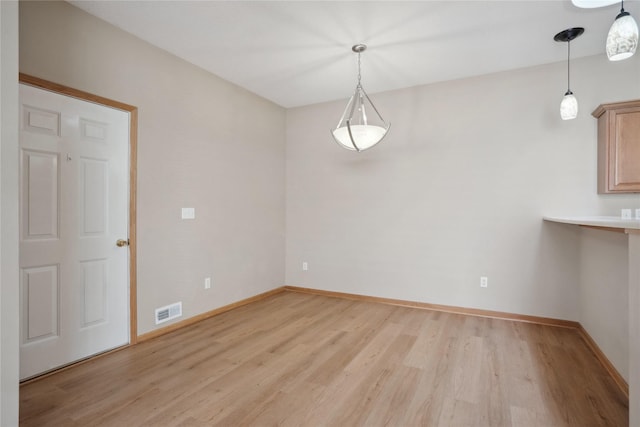 unfurnished dining area featuring light wood-style flooring and baseboards