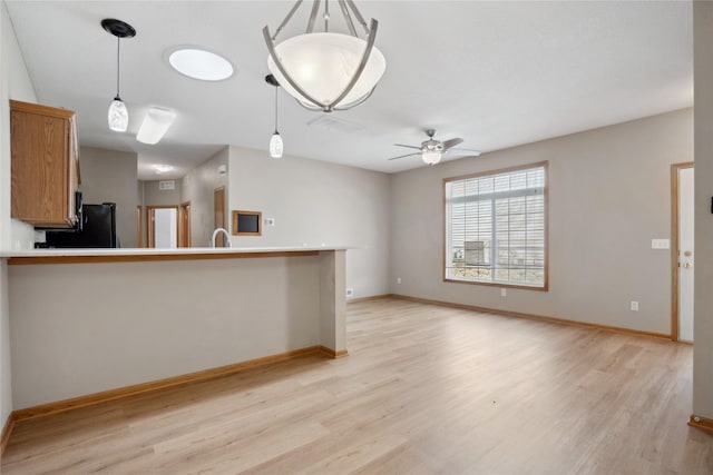 unfurnished living room featuring light wood-style floors, a ceiling fan, and baseboards