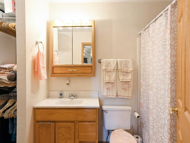 bathroom with toilet, vanity, and a shower with shower curtain