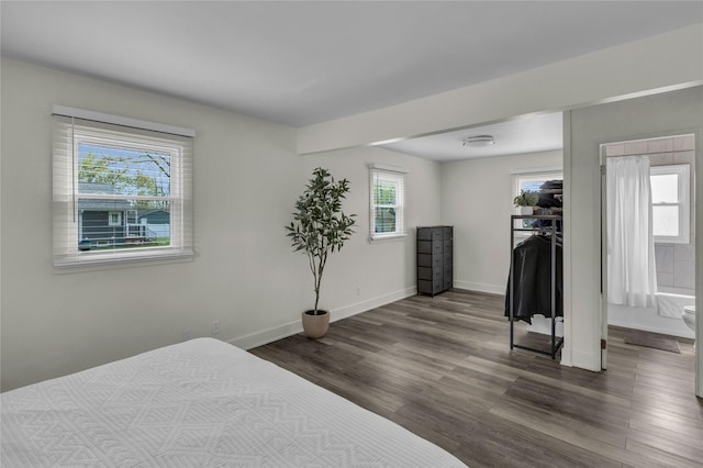 bedroom featuring dark wood-style flooring, baseboards, a walk in closet, and a closet
