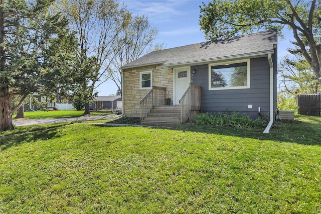 bungalow with a front yard, stone siding, and a shingled roof