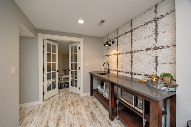 bar area with french doors, a sink, baseboards, wood finished floors, and recessed lighting