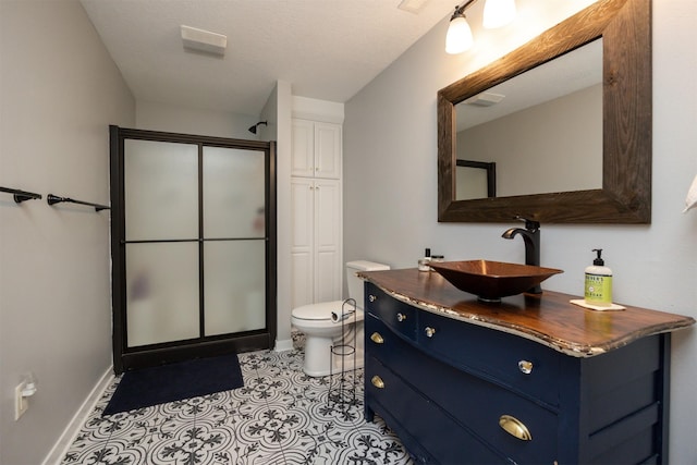 bathroom featuring toilet, a stall shower, baseboards, and vanity
