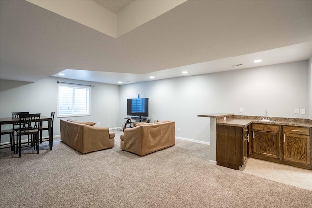 living area with light carpet, bar with sink, recessed lighting, and baseboards