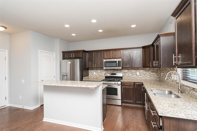 kitchen featuring stainless steel appliances, a sink, dark wood-type flooring, a center island, and recessed lighting