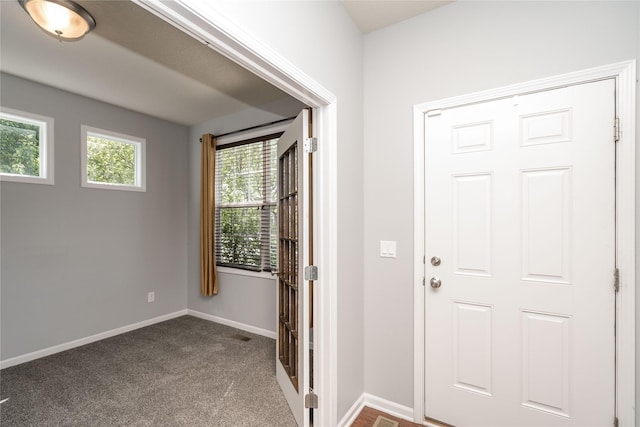 doorway to outside featuring dark colored carpet and baseboards