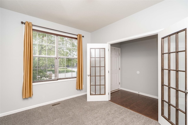 spare room with french doors, dark carpet, and baseboards
