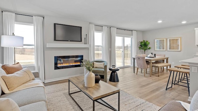 1415 Northview Dr, Waukee, IA 50263 - living room featuring a glass covered fireplace, light wood-style flooring, recessed lighting, and baseboards