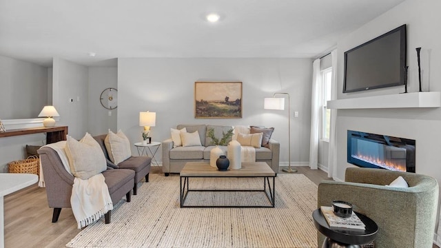 1415 Northview Dr, Waukee, IA 50263 - living room featuring light wood-style flooring, a glass covered fireplace, and baseboards