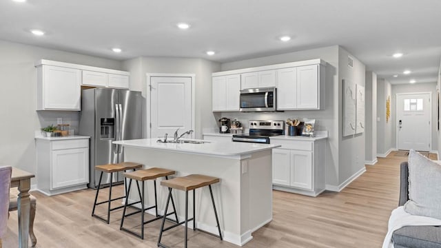 1415 Northview Dr, Waukee, IA 50263 - kitchen with appliances with stainless steel finishes, light countertops, light wood finished floors, baseboards, and a breakfast bar