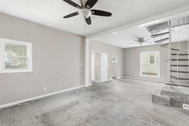 1360 E 9th St, Des Moines, IA 50316 - unfurnished living room with a ceiling fan, stairs, carpet floors, and a textured ceiling