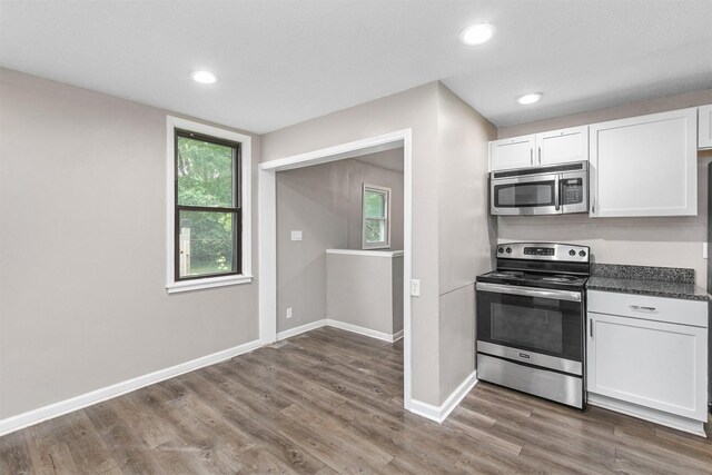 1360 E 9th St, Des Moines, IA 50316 - kitchen with stainless steel appliances, white cabinetry, wood finished floors, dark countertops, and recessed lighting