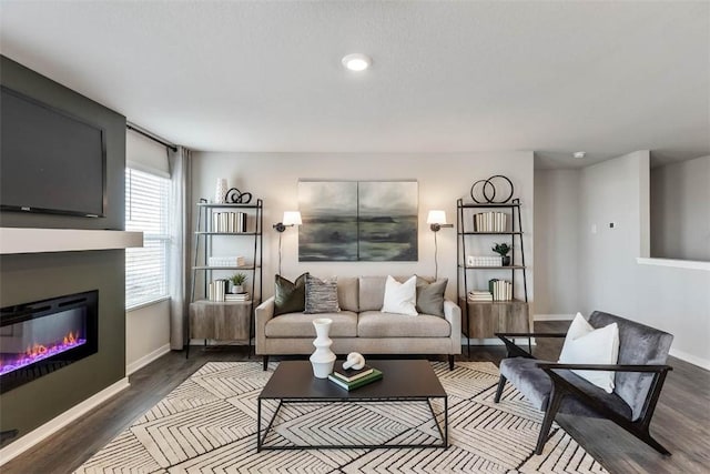 living area featuring wood finished floors, baseboards, a glass covered fireplace, and recessed lighting