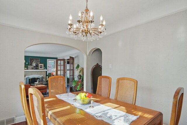 1534 41st St, Des Moines, IA 50311 - dining space with arched walkways, a chandelier, a fireplace, and crown molding