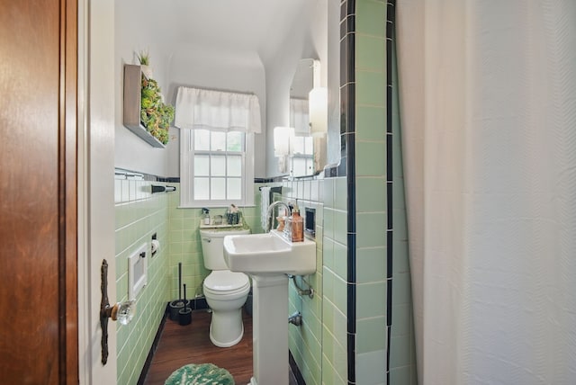 1534 41st St, Des Moines, IA 50311 - bathroom with wood finished floors, tile walls, a shower with shower curtain, toilet, and a sink