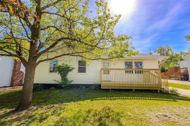 rear view of house with a lawn and a wooden deck
