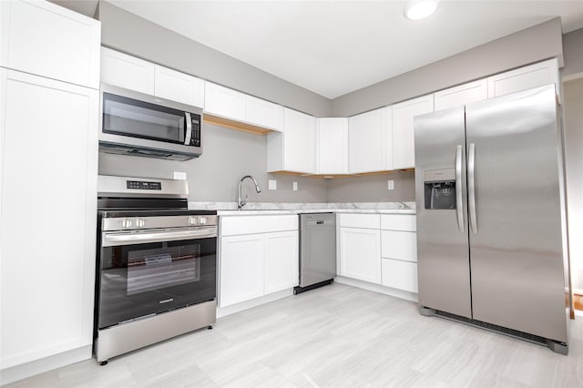 kitchen with stainless steel appliances, a sink, and white cabinetry