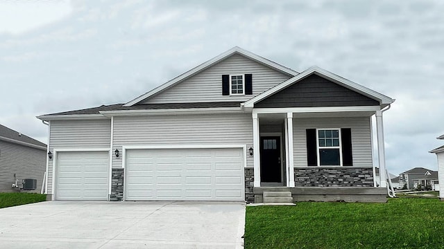 view of front of home featuring stone siding, driveway, covered porch, an attached garage, and a front lawn