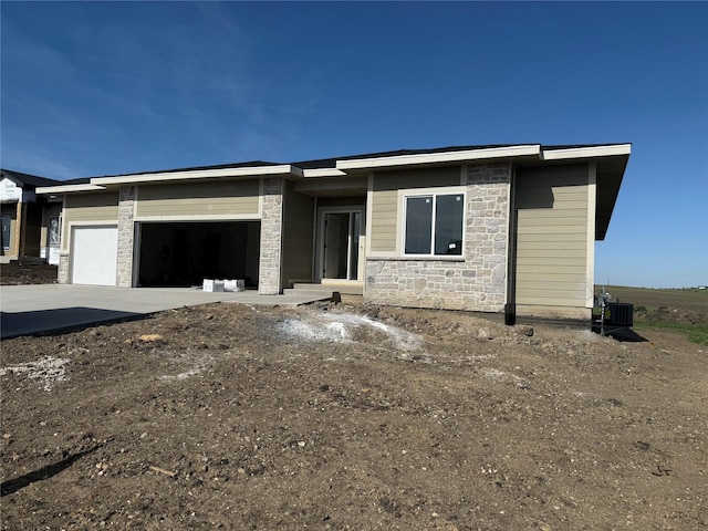 view of front of home with stone siding, a garage, and driveway