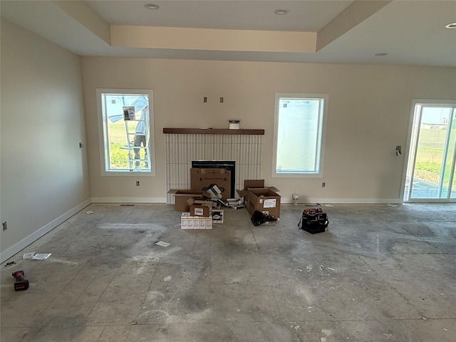 unfurnished living room with a brick fireplace, healthy amount of natural light, and baseboards
