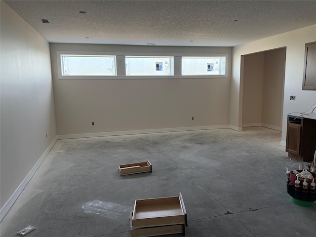 empty room featuring baseboards, a textured ceiling, and concrete flooring