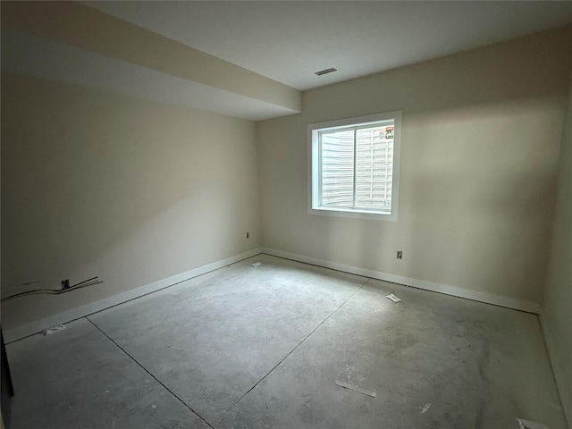 spare room featuring unfinished concrete floors and baseboards