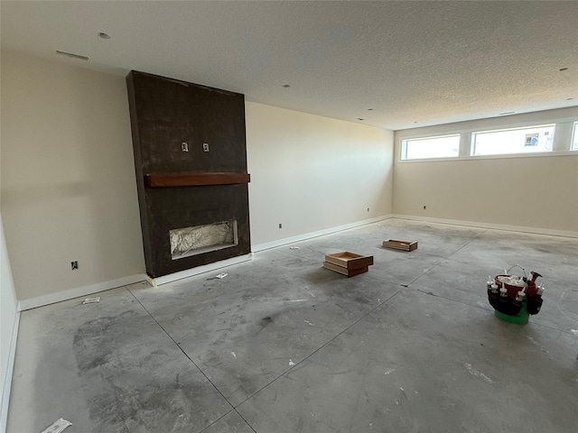 unfurnished living room featuring a fireplace, concrete floors, baseboards, and a textured ceiling