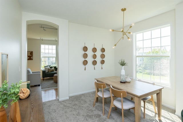 213 Bridgewood Dr, West Des Moines, IA 50266 - dining space featuring light carpet, a chandelier, and arched walkways