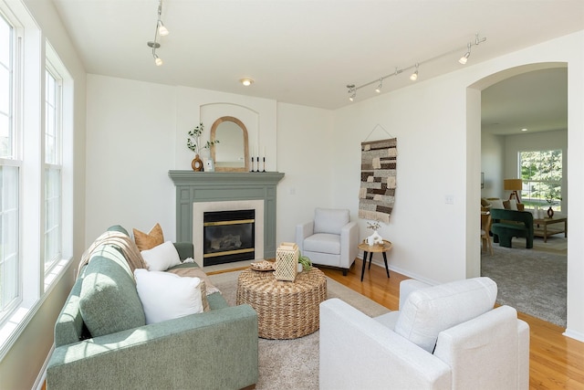 213 Bridgewood Dr, West Des Moines, IA 50266 - living area featuring rail lighting, arched walkways, a tiled fireplace, and light wood-type flooring