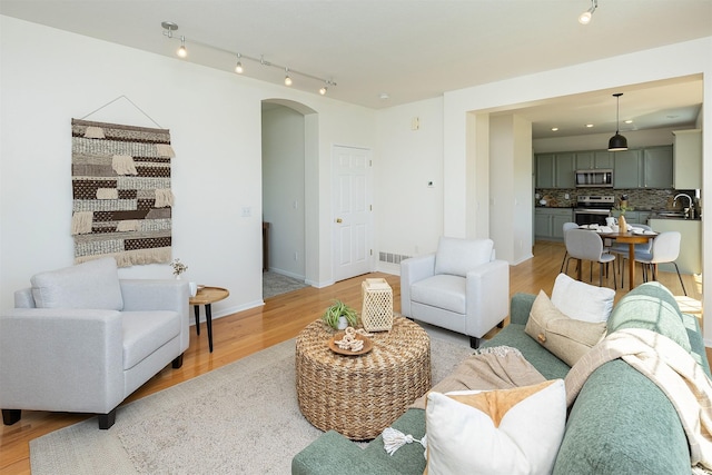 213 Bridgewood Dr, West Des Moines, IA 50266 - living room with arched walkways, light wood-style flooring, and track lighting