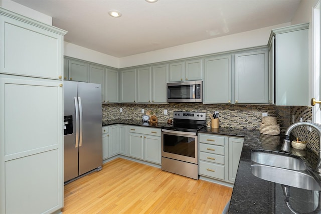 213 Bridgewood Dr, West Des Moines, IA 50266 - kitchen featuring appliances with stainless steel finishes, dark stone countertops, decorative backsplash, light wood-style floors, and gray cabinets