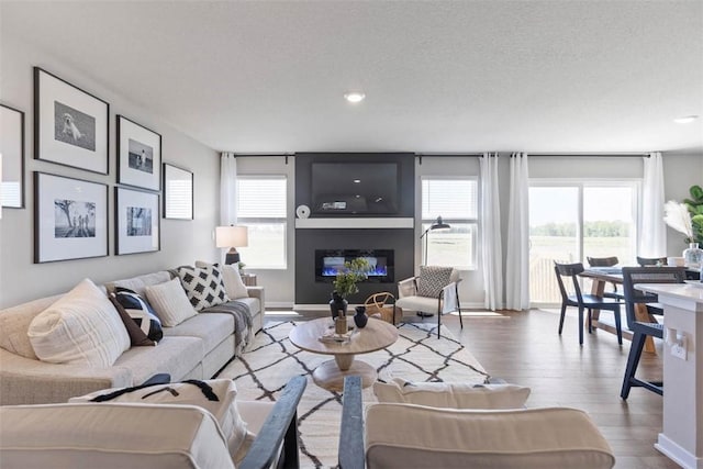 living room with a glass covered fireplace, recessed lighting, wood finished floors, and baseboards