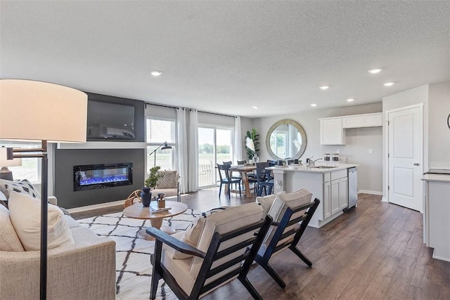 living room with a textured ceiling, recessed lighting, a glass covered fireplace, and wood finished floors