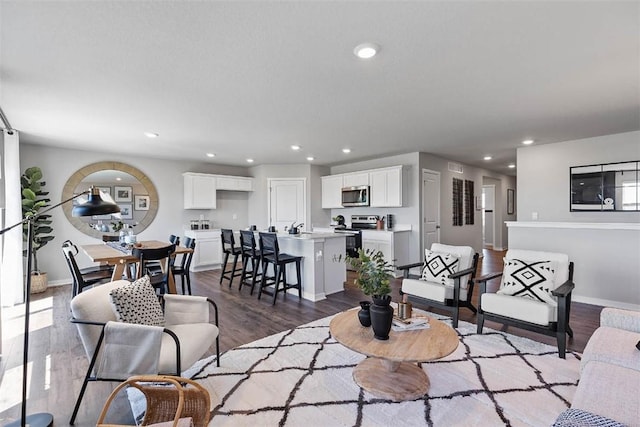 living room featuring dark wood finished floors, baseboards, and recessed lighting